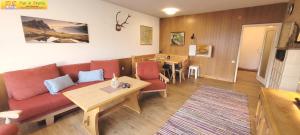 ein Wohnzimmer mit einem roten Sofa und einem Tisch in der Unterkunft Bungalow Irmgard by FiS - Fun in Styria in Bad Mitterndorf