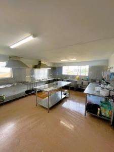 eine große Küche mit Tischen und Arbeitsflächen aus Edelstahl in der Unterkunft CALI Backpackers in Caloundra