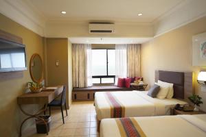 a hotel room with two beds and a desk at Corus Paradise Resort Port Dickson in Port Dickson