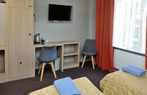 een kamer met 2 stoelen en een bureau met een televisie bij HOTEL MOTEL S5 in Bydgoszcz
