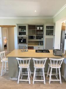 a kitchen with a counter and four bar stools at Beach front Rocky Pools in Bettyʼs Bay