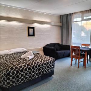 Habitación de hotel con cama y sofá en Wangaratta Motor Inn, en Wangaratta