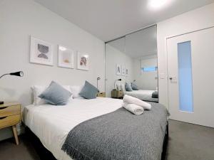 1 dormitorio con 2 camas y un espejo grande en Merchant Apt by GoodLive, en Melbourne
