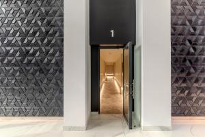 un pasillo con una puerta que da a un pasillo con paredes blancas y negras en Infinite Horizons - Modern Living in North Business District, en Bucarest