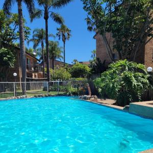 a swimming pool in a yard with palm trees at Reef Resort Apartments in Mona Vale +11 photos