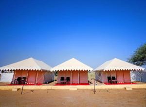 a row of tents with white roofs in a field at Husain desert Safari Camp in Jaisalmer