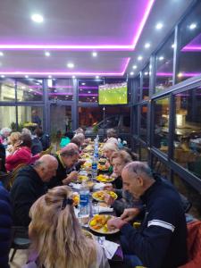 un grupo de personas sentadas en una mesa larga comiendo comida en Hôtel Imilchil en Midelt