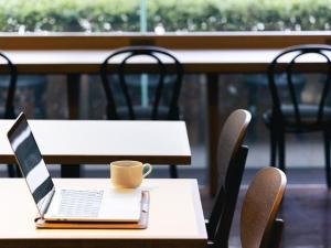 um computador portátil numa mesa com uma chávena de café em Mitsui Garden Hotel Okayama em Okayama