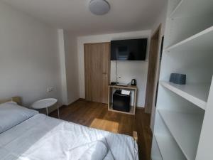 1 dormitorio con cama, mesa y TV en Penzion U Kovárny, en Malá Morávka
