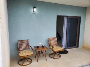 2 Stühle und ein Tisch in einem Zimmer mit einer Wand in der Unterkunft Tropical Rose Getaway in Discovery Bay