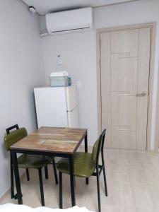 uma cozinha com uma mesa e cadeiras e um frigorífico em Ara Guesthouse em Busan