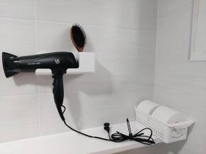 a black hair dryer on a shelf in a bathroom at Ara Guesthouse in Busan