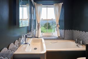 ein Bad mit einem Waschbecken, einer Badewanne und einem Fenster in der Unterkunft Host & Stay - Prospect Cottage in Newby Bridge