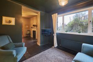 ein Wohnzimmer mit einem Sofa, einem TV und einem Fenster in der Unterkunft Host & Stay - Prospect Cottage in Newby Bridge