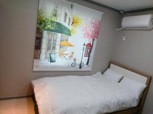 um quarto com uma cama com um quadro na parede em Ara Guesthouse em Busan