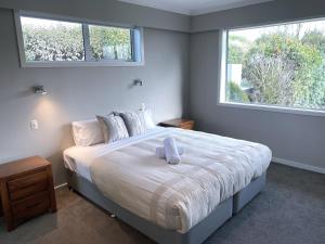 a bedroom with a large bed with two windows at Prebbleton lifestyle Villa in Prebbleton