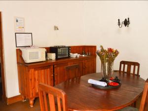 una mesa con microondas y un jarrón de flores. en Zandvlakte Guest Farm, en Studtis