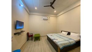 sypialnia z łóżkiem, telewizorem i krzesłem w obiekcie Srinivasan Villa w mieście Waranasi