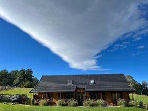 a house with a black roof on a green field at Osada Karkonoska in Kowary