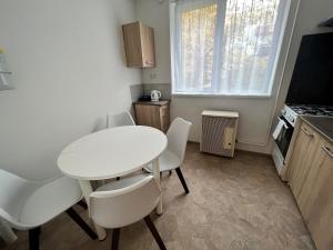 una pequeña cocina con mesa blanca y sillas en Karman Apartman - 2 bedroom entire flat in the center, en Jászberény