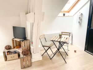 a living room with a table and a tv and a chair at Charmant studio paisible in Alençon