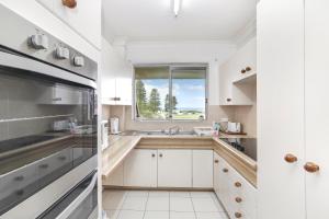 a white kitchen with a sink and a window at Reef Resort Apartments in Mona Vale