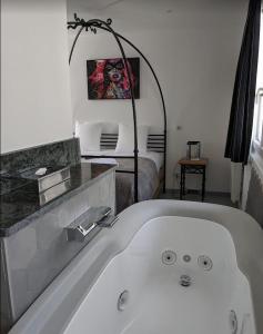 een wit bad in een kamer met een bed bij Hotel et Spa Le Lion d'Or in Pont-lʼÉvêque