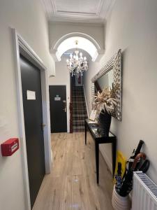 a hallway with a chandelier and a table with a mirror at Elizabeth Grace House in Douglas