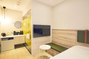 a room with a bed and a tv and a table at CHECK Inn Express New Taipei Tamsui in Tamsui