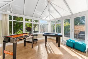 a room with a ping pong table and windows at Stunning House in Bracknell - Garden - Games room in Bracknell