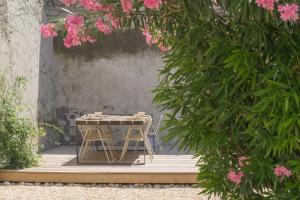 una mesa y taburetes en una terraza de madera con flores rosas en TRIBUS-GITES URBAINS CARCASSONNE en Carcasona