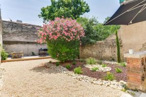 un jardin avec des fleurs roses et un mur en pierre dans l'établissement TRIBUS-GITES URBAINS CARCASSONNE, à Carcassonne