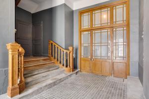 - un couloir avec une porte en bois et des escaliers dans l'établissement TRIBUS-GITES URBAINS CARCASSONNE, à Carcassonne