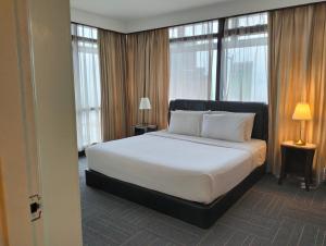 a bedroom with a large white bed with windows at Luxy Service Apartment at Times Square KL in Kuala Lumpur