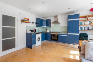 eine Küche mit blauen Schränken, einer Waschmaschine und einem Trockner in der Unterkunft Well located 1 bed Angel/Kings Cross pad in London