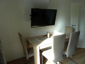 einen Esstisch mit Stühlen und einen TV an der Wand in der Unterkunft Ferienwohnung Klose in Schmallenberg