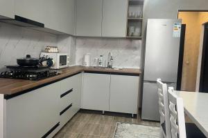 a kitchen with white cabinets and a white refrigerator at Apartament Manasa in Bishkek