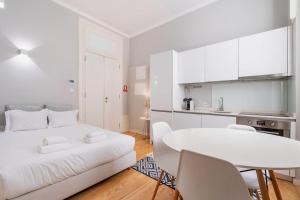 een witte kamer met een wit bed en een tafel bij Cozy Studio Arts Porto Downtown in Porto