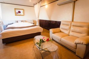 ein Schlafzimmer mit einem Bett, einem Sofa und einem Tisch in der Unterkunft Santa no Ouchi-LoveHotel in Miyazaki