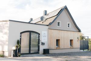 a white house with a black door at Pension Blumenwiese - Mitten im Thermenland in Burgau