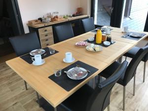 a wooden table with chairs and plates of food on it at Le Manoir de l'Oselière & Spa in Les Hauts-Geneveys