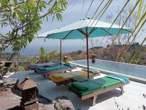 a pool with several lounge chairs and an umbrella at Private Villa - Ocean, hills, valley view in Temukus