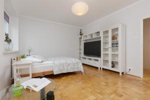 een witte slaapkamer met een bed en een televisie bij Studio Bielany with Home Office near Metro Station by Renters in Warschau