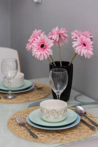 een tafel met borden en glazen en een vaas met roze bloemen bij Studio Bielany with Home Office near Metro Station by Renters in Warschau