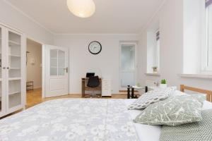 een witte slaapkamer met een bed en een klok aan de muur bij Studio Bielany with Home Office near Metro Station by Renters in Warschau