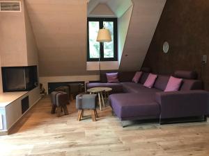 ein Wohnzimmer mit einem lila Sofa und einem TV in der Unterkunft Le Manoir de l'Oselière & Spa in Les Hauts-Geneveys