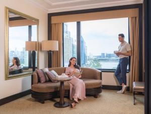 a man and a woman sitting in a room with a window at Sheraton Grande Sukhumvit, a Luxury Collection Hotel, Bangkok in Bangkok