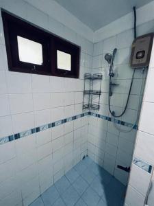 baño de azulejos blancos con ducha y ventana en bungalow, en Nathon Bay