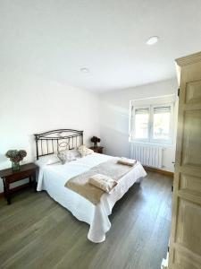 a white bedroom with a bed and a window at Maysa in Santillana del Mar