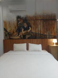 a bedroom with a bed with a painting on the wall at Ladja Hotel Sintang in Sintang +12 photos